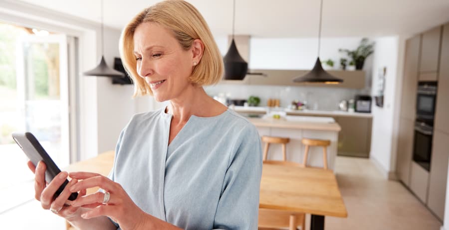 Homeowner using a smartphone in a room filled with sunlight